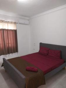 a bedroom with a large bed with red sheets at Cozy Place in Port Louis