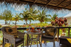 a table and chairs on a balcony with a view of the ocean at Tai Roto Bay in Arutanga