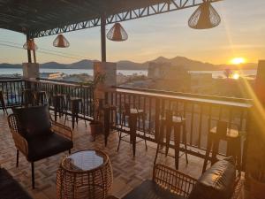 - un bar avec des chaises et des tables sur un balcon offrant une vue sur le coucher du soleil dans l'établissement ISLANDERS INN - CORON, à Coron