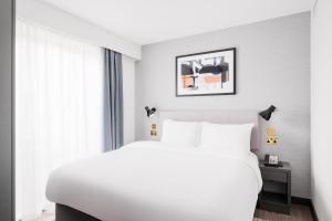 um quarto com uma cama branca e uma janela em Staybridge Suites Brighton, an IHG Hotel em Brighton & Hove