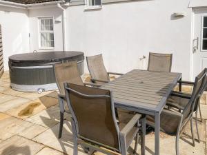 een tafel en stoelen op een patio met een hot tub bij Beech Cottage - Uk11845 in Saltash