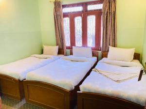 3 camas en una habitación con ventana en HOTEL ICE VIEW POKHARA, en Pokhara