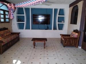 a living room with a couch and a tv on a wall at Casa Jeymar in Coyuca