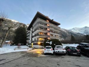 un bâtiment avec des voitures garées dans un parking dans l'établissement Résidence Bois du Bouchet, appartement vue montagne, calme, parking gratuit, proche centre, à Chamonix-Mont-Blanc