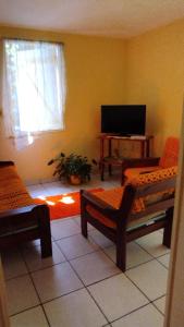 ein Wohnzimmer mit 2 Stühlen und einem Flachbild-TV in der Unterkunft La Creoline 01 in Pointe-Noire