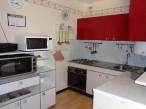 Kuchnia wyposażona jest w czerwono-białe szafki oraz kuchenkę mikrofalową. w obiekcie Studio cosy avec balcon et parking - Proche cures et centre ville, Wifi, animaux acceptés - FR-1-703-39 w mieście Amélie-les-Bains-Palalda