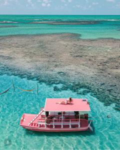 a pink boat in the water near a beach at Casa Mara Milagres in Passo de Camarajibe