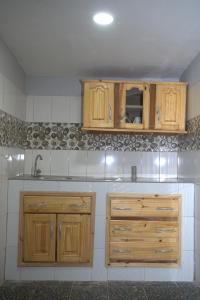una cocina con armarios de madera y fregadero en Faith and Grace Guest House, en Lamin