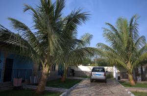 a car parked between two palm trees in a driveway at Faith and Grace Guest House in Lamin