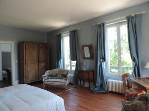 a bedroom with a bed and a table and windows at Chambres d'Hôtes de la Bucaille in La Bucaille