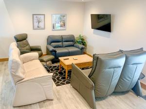 ein Wohnzimmer mit Stühlen, einem Sofa und einem Tisch in der Unterkunft Dronefield Lodge in Pitney