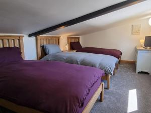 Dronefield Lodge في Pitney: غرفة نوم بسريرين ذات أغطية أرجوانية