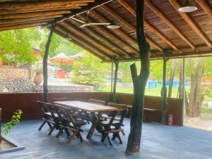 a wooden table and chairs under a wooden roof at Complejo Las Violetas in Merlo