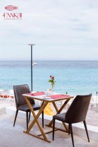 een tafel en stoelen met het strand op de achtergrond bij ENNKAI Beachfront Resort Koh Larn in Pattaya