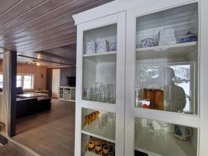 a glass cabinet with bottles and glasses in a room at Tangen - cabin with 4 bedrooms - great nature in Norheimsund