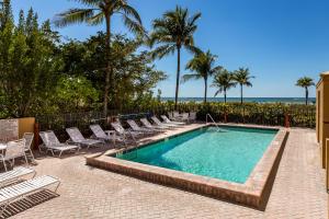 uma piscina com espreguiçadeiras e palmeiras em Estero Island Beach Villas 204, Sleeps 8, 2 Bedrooms, Gulf Front, Heated Pool em Fort Myers Beach