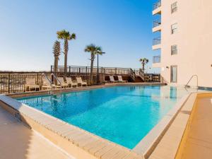 a swimming pool with chairs and a building at Ocean Breeze West #204 in Perdido Key