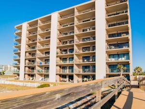 a large white building with a wooden walkway in front of it at Ocean Breeze West #204 in Perdido Key
