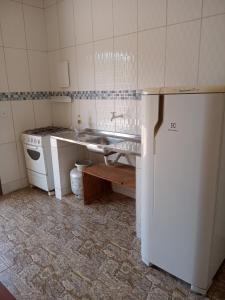 a kitchen with a sink and a white refrigerator at ApartHotel Família Meireles in Luziânia