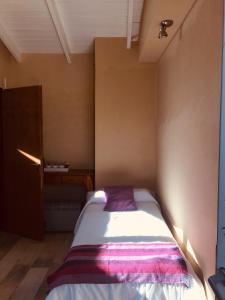 a small bedroom with a bed with a purple blanket at Cabañas Aparts Tierra de Glaciares in El Calafate