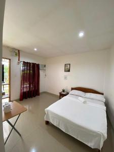 a bedroom with a large white bed and a table at Casa Oeste in Moalboal