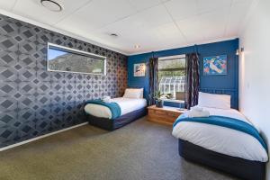 Duas camas num quarto com paredes azuis e uma janela em Remarkable View 4 Bedroom em Queenstown