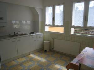 kuchnia z białymi szafkami, umywalką i oknami w obiekcie Appartement F2 avec Terrasse et Parking, Proche Cures et Centre-ville - Amélie-les-Bains - FR-1-703-142 w mieście Amélie-les-Bains-Palalda