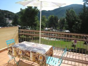 stół i krzesła na balkonie z parasolem w obiekcie Appartement F2 avec Terrasse et Parking, Proche Cures et Centre-ville - Amélie-les-Bains - FR-1-703-142 w mieście Amélie-les-Bains-Palalda