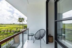 einen Balkon mit 2 Stühlen und Blick auf ein Feld in der Unterkunft 2BR Pool Villa Alba in Canggu, Rice field view in Dalung