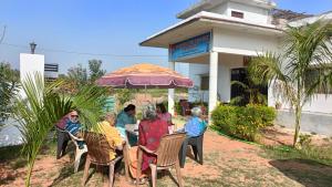 Un groupe de personnes assises à une table sous un parapluie dans l'établissement The Mountain View Home Stay, à Khajurâho