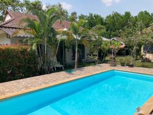 a swimming pool in front of a house at Vacation House with tropical garden and private pool in Rayong