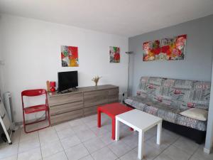 a living room with a couch and a red chair at Appartement Le Grau-du-Roi, 2 pièces, 6 personnes - FR-1-307-8 in Le Grau-du-Roi