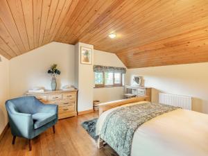 een slaapkamer met een bed en een blauwe stoel bij Barn House in Friskney