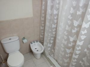 a bathroom with a toilet and a shower curtain with butterflies at COMPLEJO ALOHA in Puerto Pirámides