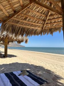 a beach with a straw umbrella and the ocean at Stella del Mar in San Felipe