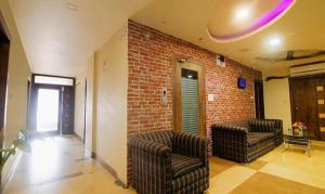 sala de estar con 2 sillas y pared de ladrillo en FabHotel Elements Inn, en Patna