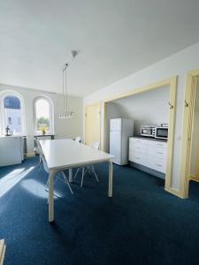 a kitchen with a white table and a white refrigerator at Spacious and beautiful apartment in the center of Frederikshavn in Frederikshavn