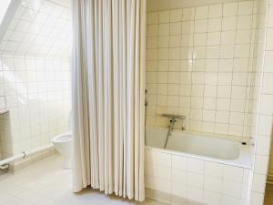 a bathroom with a bath tub and a toilet at Spacious and beautiful apartment in the center of Frederikshavn in Frederikshavn