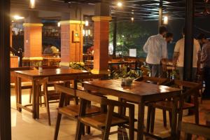 a group of wooden tables and chairs in a restaurant at SkyLounge Residency in Trivandrum