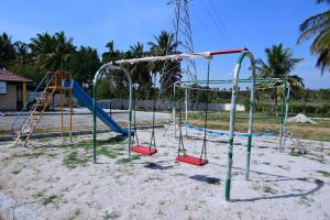 an empty playground with two swings and a slide at Encanto Farmstay in Mysore