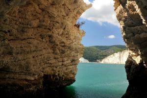 a view of the water through a rock cave at Matinee Rooms in Mattinata