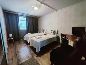 a hotel room with two beds and a television at Kartanomajoitus Sofia & Angelique in Pieksamaki