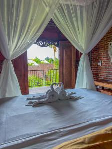 two swans sitting on a bed in a bedroom at Lemon Guest House in Canggu