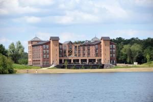 a large brick building next to a body of water at Parkhotel Horst - Venlo in Horst