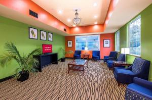 a waiting room with green and orange walls and blue chairs at MY HOME & SUITES MADISON GA in Madison