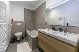 a bathroom with a sink and a toilet and a mirror at Les appartements de Clélia in Ax-les-Thermes