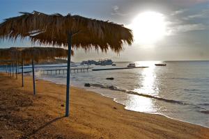 a beach with a straw umbrella and the ocean at Umbi Sharks Bay Diving Village in Sharm El Sheikh