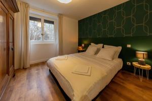 a bedroom with a large bed with a green wall at Les appartements de Clélia in Ax-les-Thermes