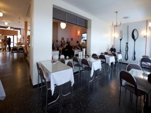 a dining room with white tables and chairs and people at Lages Motel in Borås