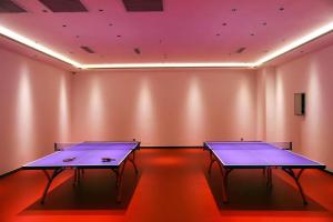 two ping pong tables in a room with pink lights at 潍坊富华大酒店a座 in Weifang